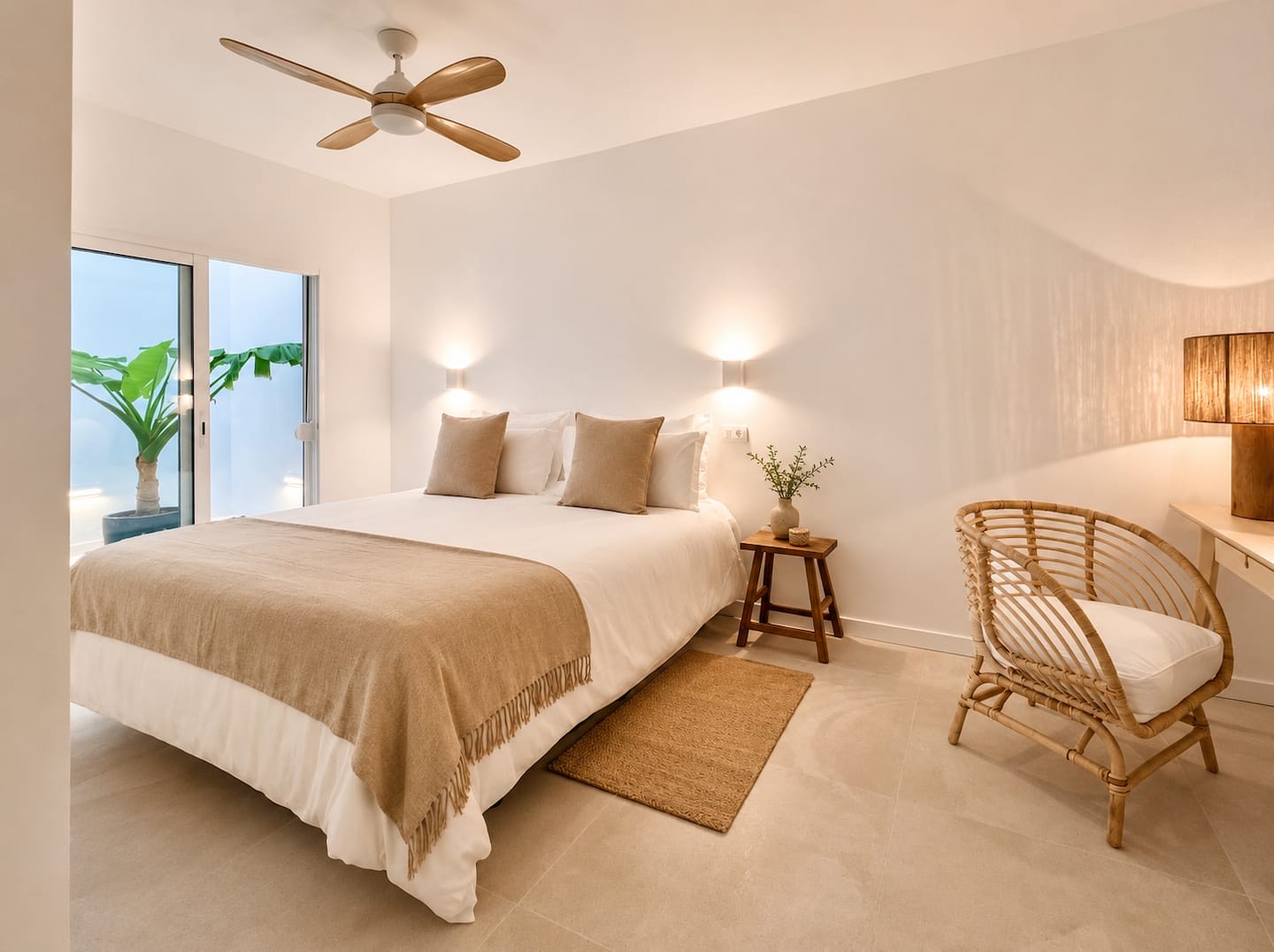 Main bedroom with a large bed, rattan armchair and ceiling fan